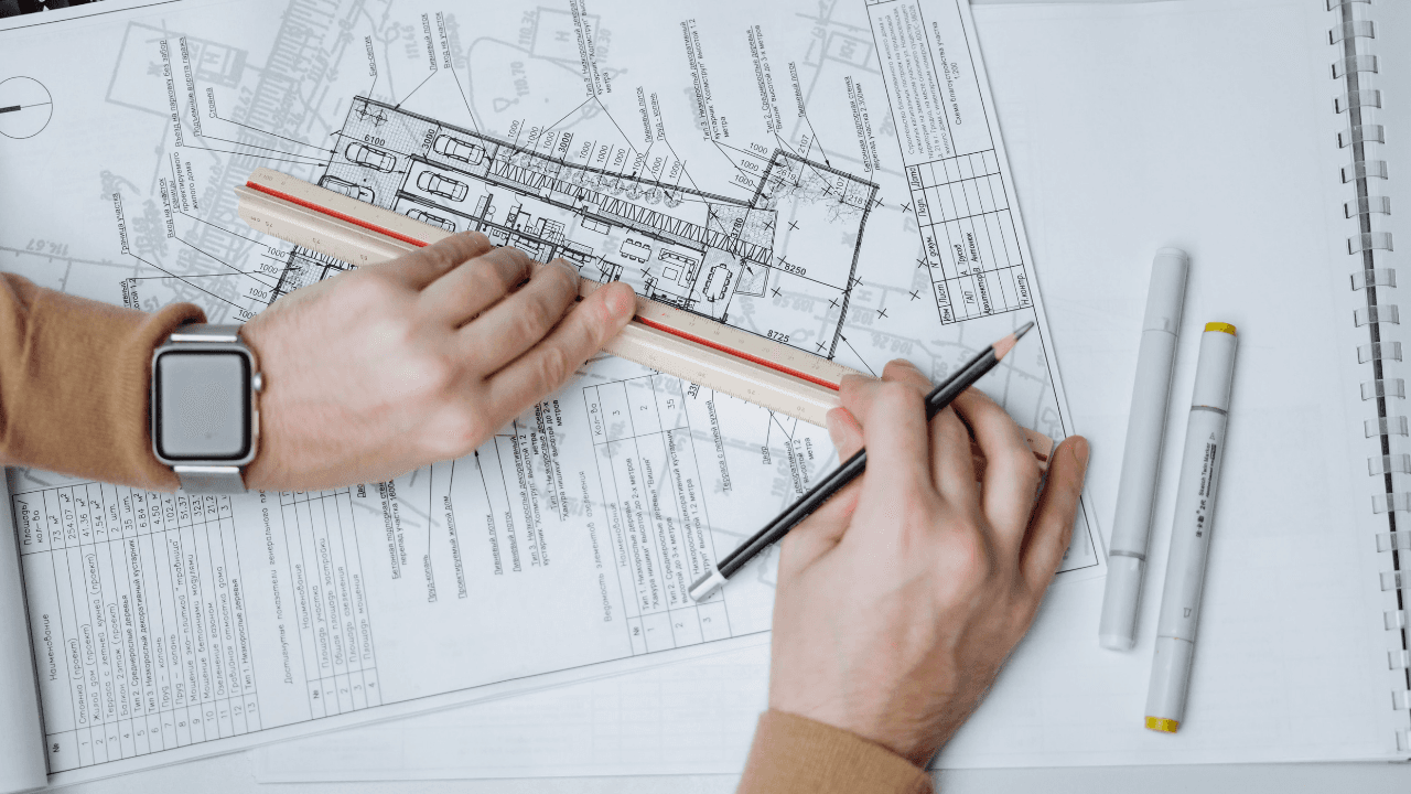 Hands drafting a technical blueprint